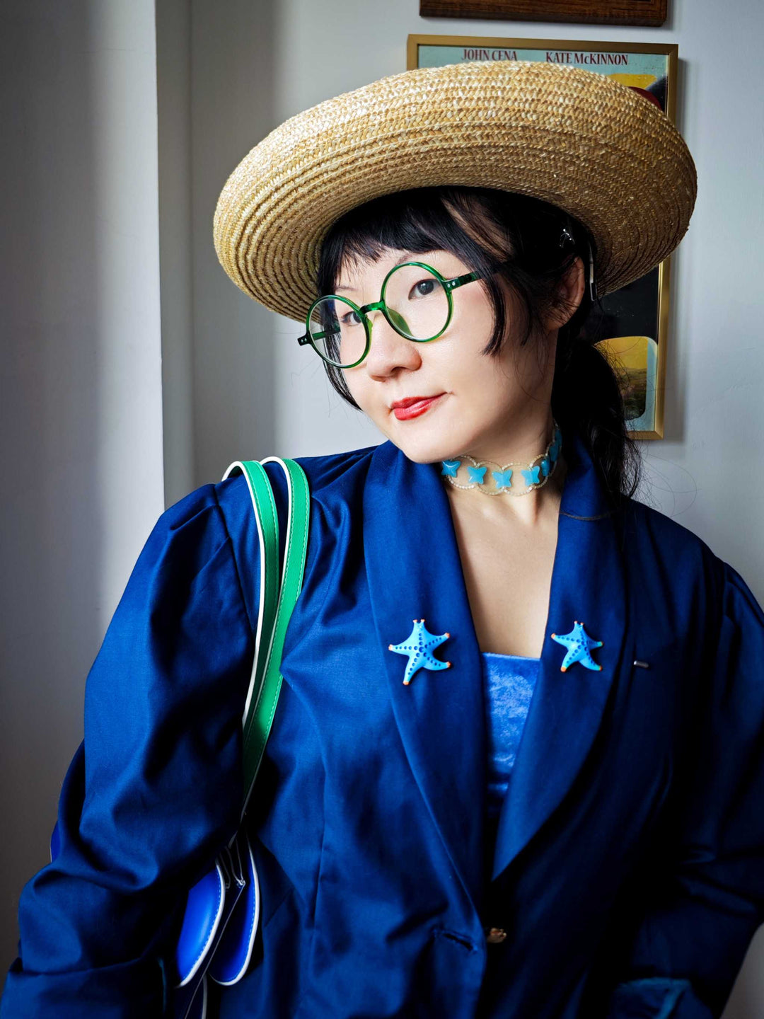 Vibrant lake blue and orange SeaStar cat hairclip and brooch worn by a person in blue attire and straw hat.