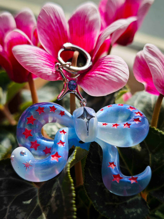 Ice blue snake bowtie accessory with red star accents and felt tongue against pink flowers