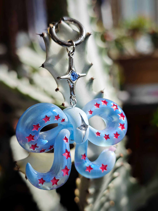 Ice blue snake bowtie earring with pink stars and silver star detail, unique playful accessory