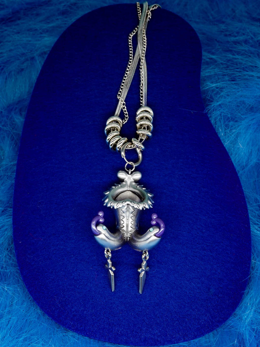 Twin-headed pitcher serpent earrings with violet tendrils and metallic spikes on silver-toned serpents
