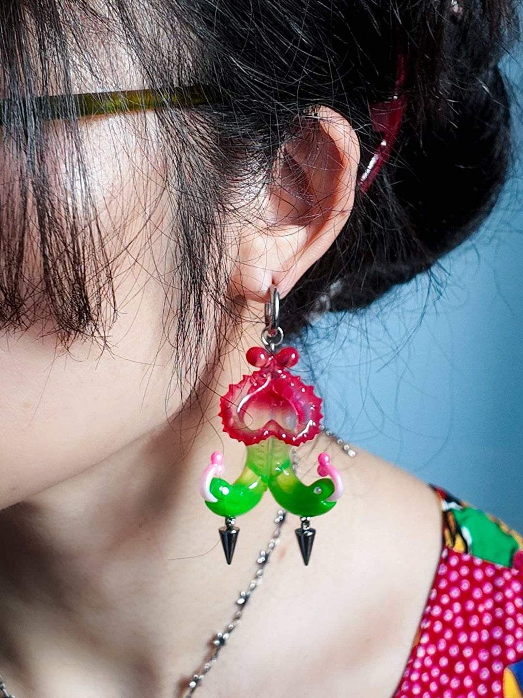 Twin-headed pitcher serpent earrings in cherry red, acid green, and bubblegum pink with metal spikes by Acid Candy