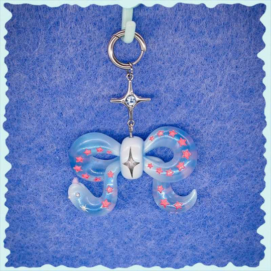 Ice blue snake bowtie necklace with pink star accents and silver star charm on blue background